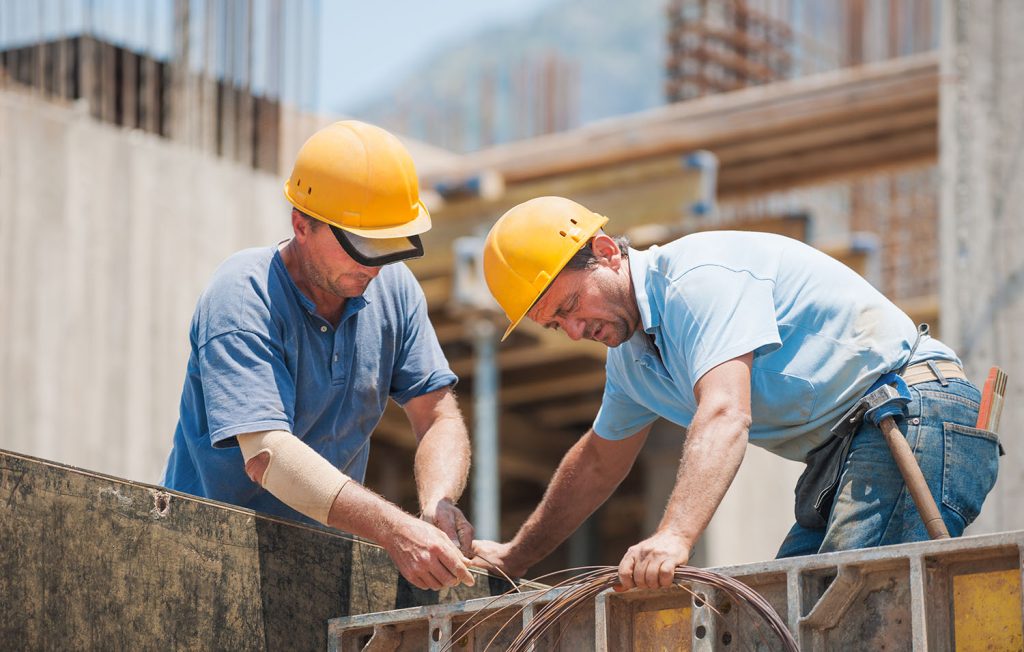 Authentic construction workers collaborating in the installation of cement formwork frames