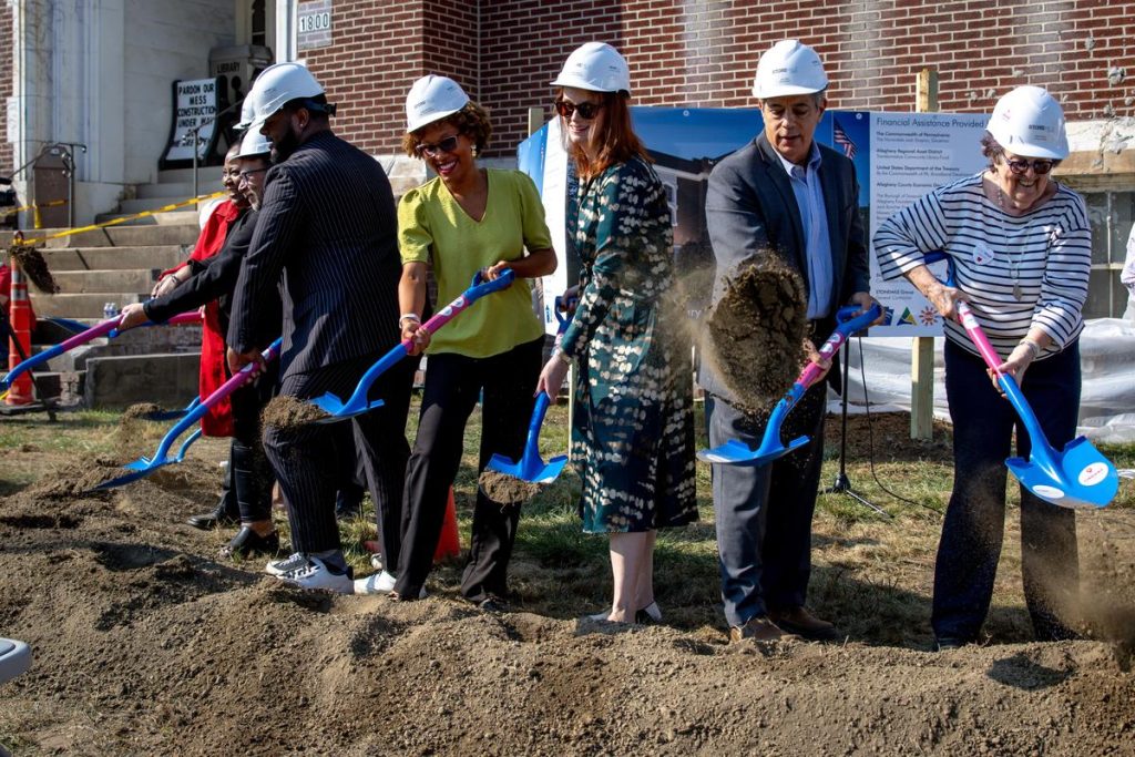 A group of professionally dressed people with hard hats and shovels
