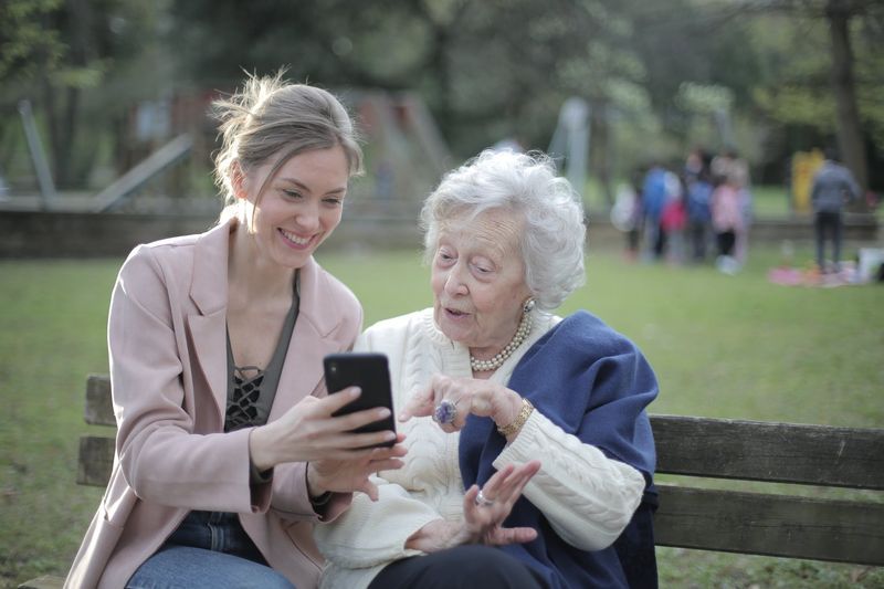 Younger and older woman looking at a phone on a park bench
